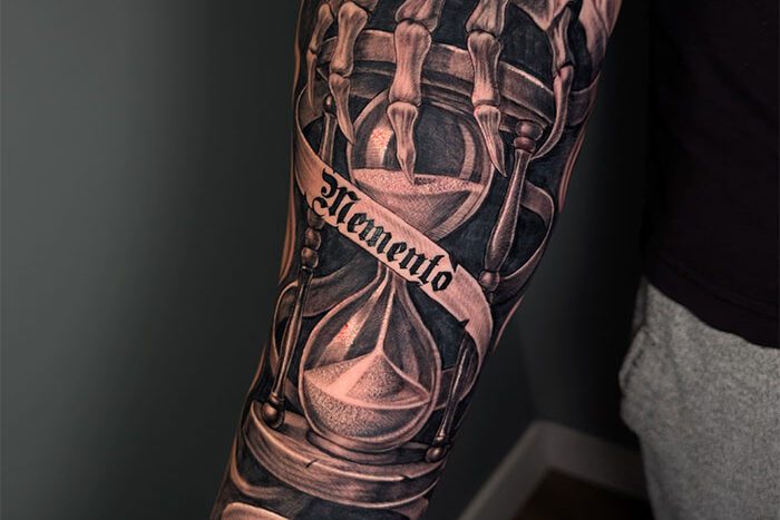 Skeleton hand holding sand timer tattoo by Aram Hryhorian