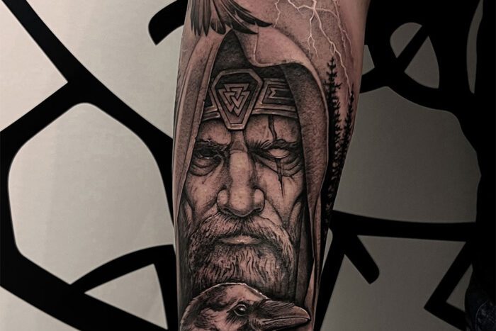 Black and grey tattoo of man in cloak