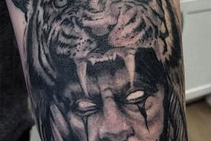 Man with tiger head hat tattoo, by Derrick Baltkalns